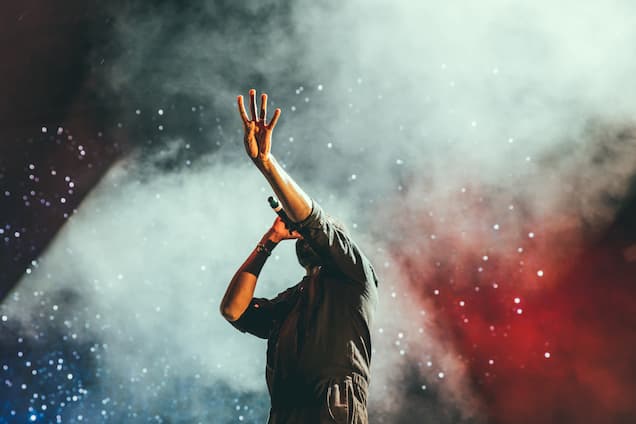Photographie d'un chanteur avec une main levée vers le ciel