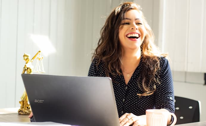 Photographie d'une employée de bureau heureuse derrière son ordinateur